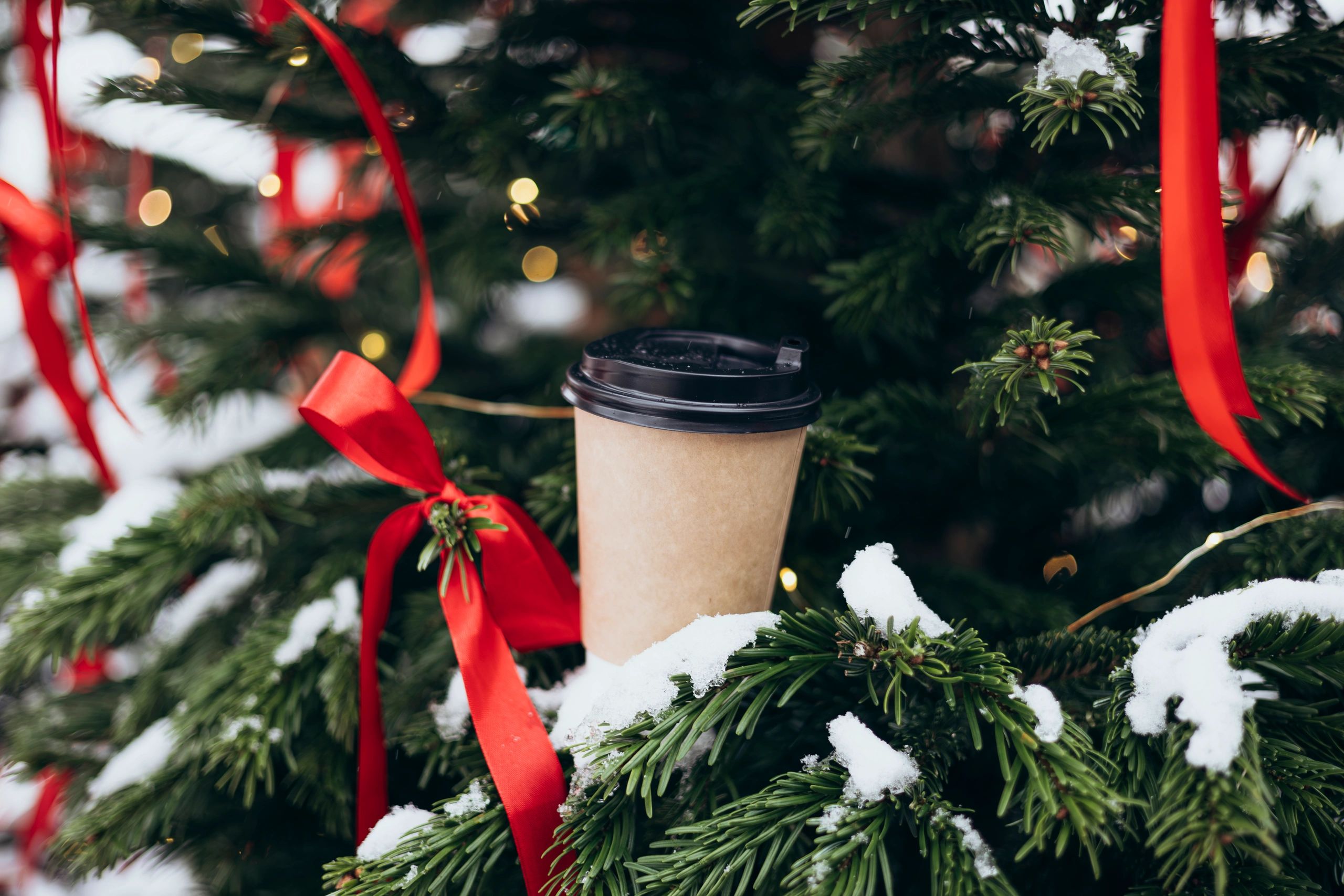 Coffee cup by a decorated Christmas tree evoking a romantic holiday reading scene