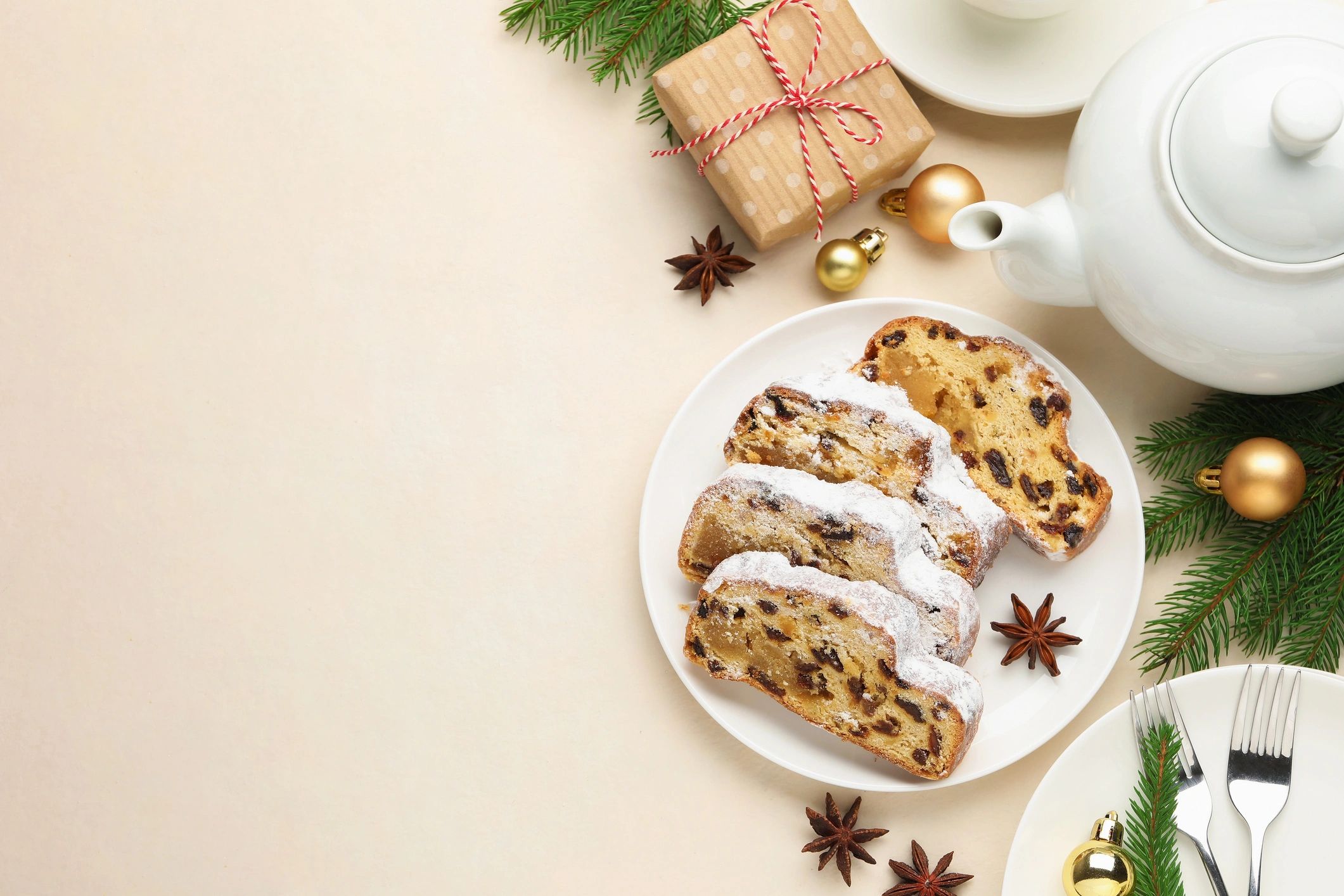 Slices of traditional stollen with teapot and Christmas decor in flat lay